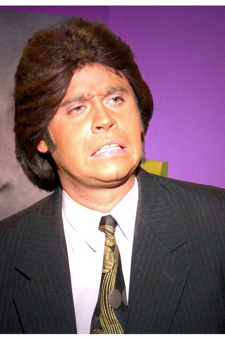 Jeringa caracterizado como cantante de balada, con peluca y traje de rayas